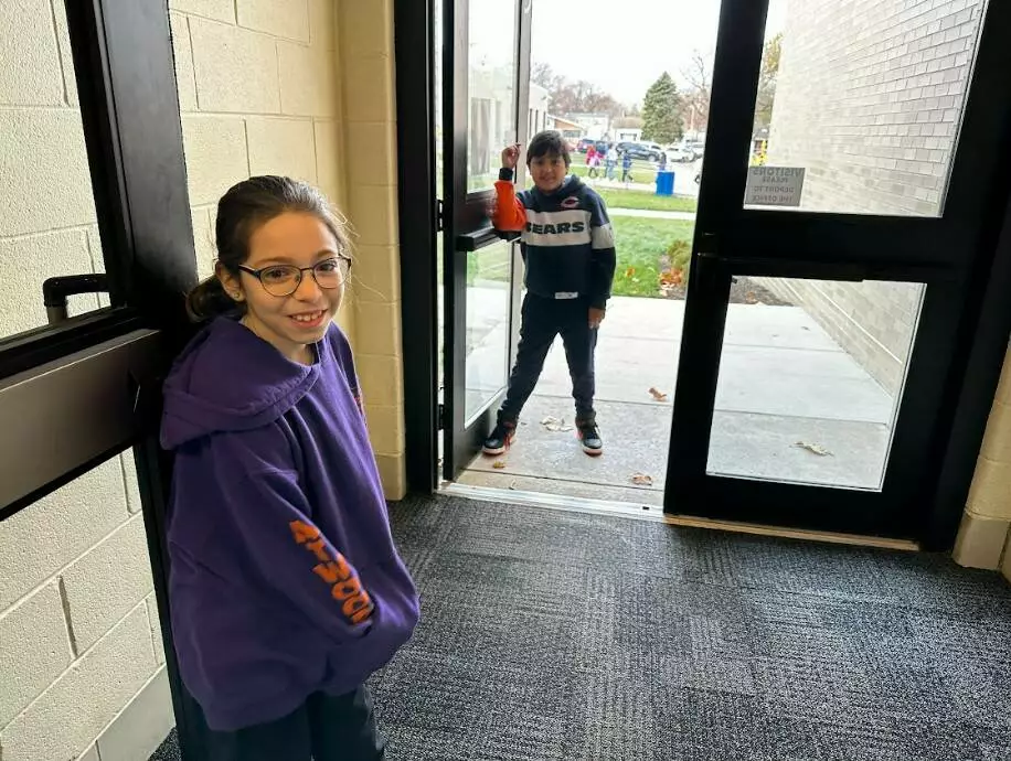 Two patrol members hold the doors open at student arrival.