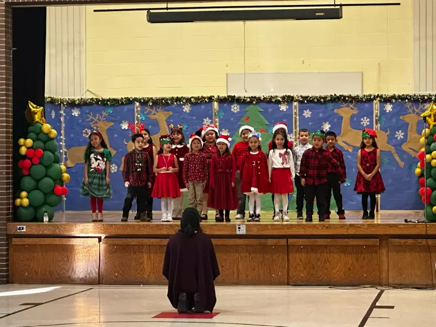 Mrs. Gonzelez leaders her first graders in their performance