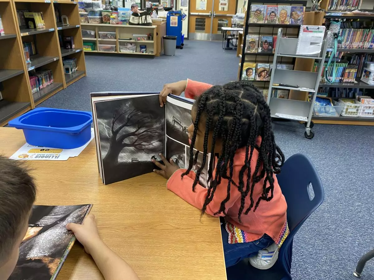 A kindergartener admires the illustrations in a Monarch nominated book.