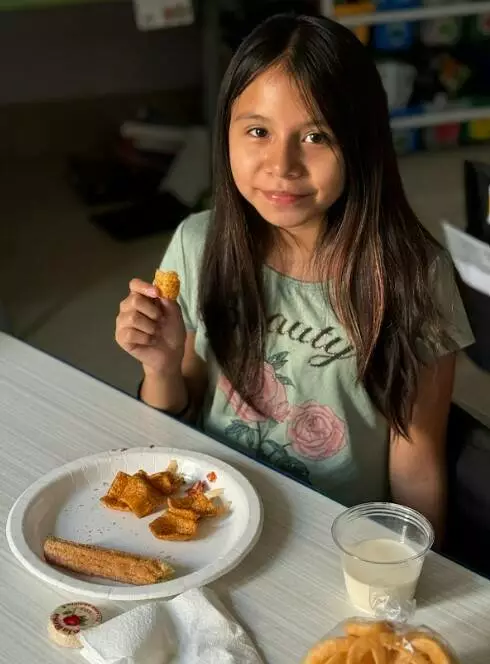 A fifth grader enjoys her plate of churro and chicharrones. 