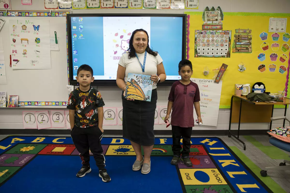 Ms. Serrano poses with two students who came to hear her read about butterflies.