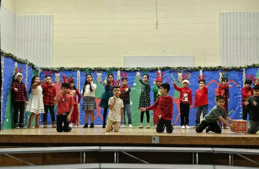 Third graders perform a traditional dance and song for their families. 