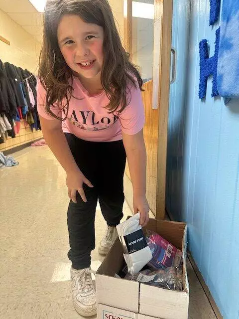 An excited third grader displays some of the many socks that have been collected