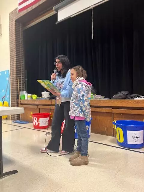 A first grader follows along while Mrs. Carpenter reads aloud to the lunchroom. 